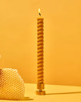Twisted candle with honeycomb on a yellow background