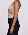 Woman wearing a beige halter top and black pants on a white background