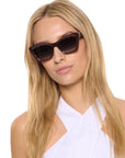 Woman wearing dark sunglasses with a plain white background