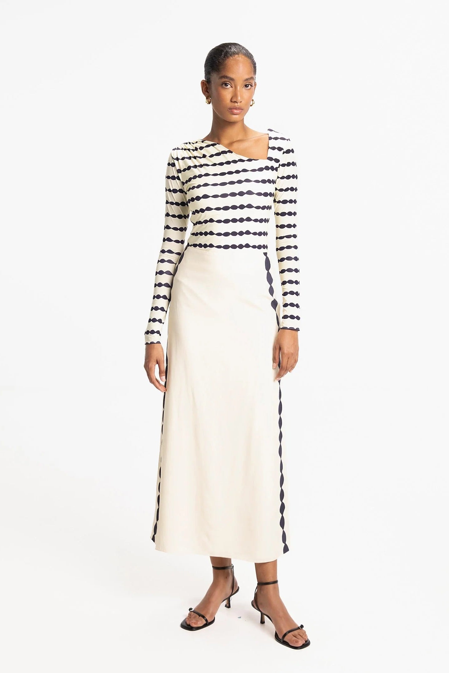 Woman wearing a Navy and white striped long-sleeve top and cream skirt on a white background