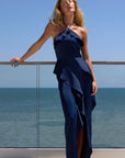 model wearing a dark blue ruffled dress by the ocean