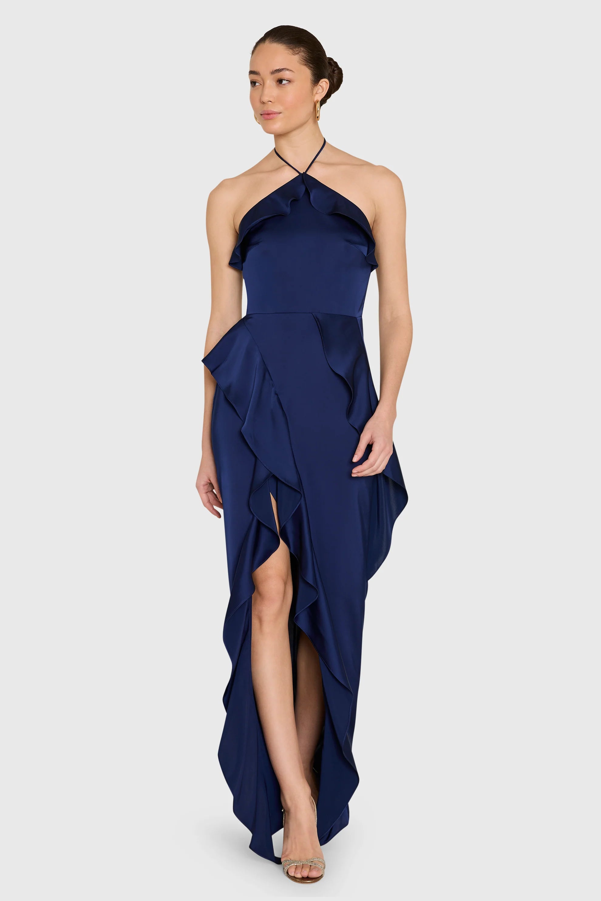 model wearing a dark blue ruffled dress on a white background