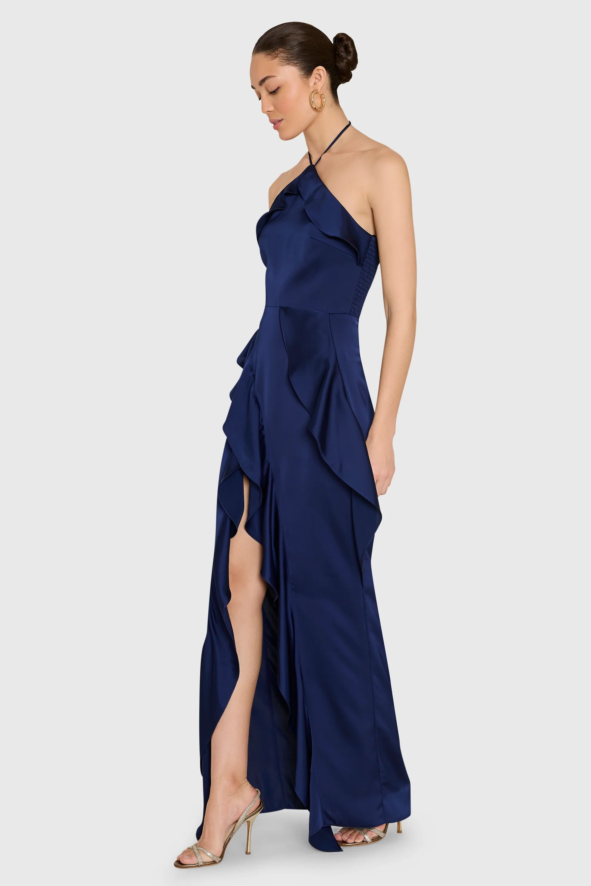 model wearing a dark blue ruffled dress on a white background