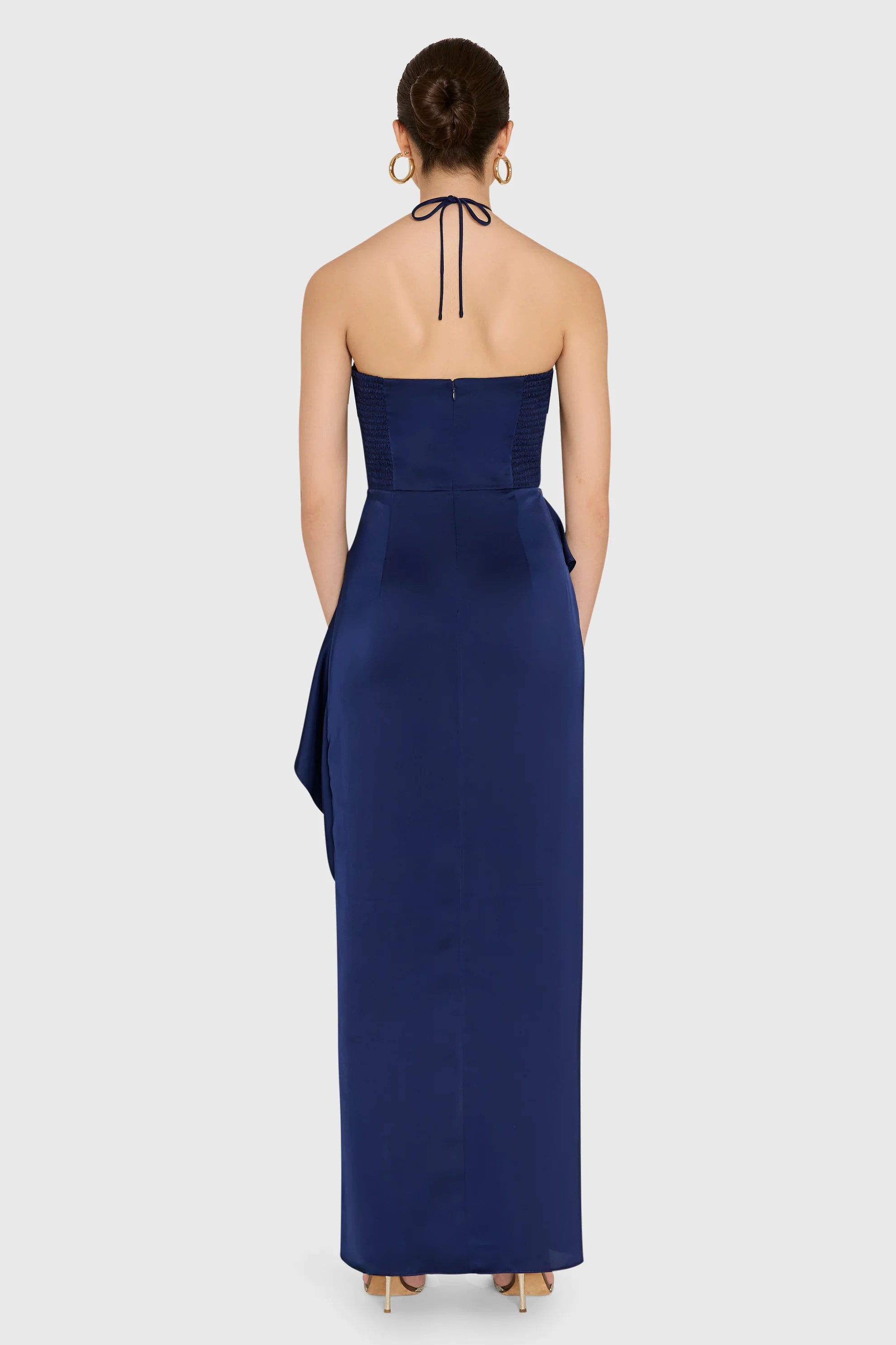 model wearing a dark blue ruffled dress on a white background, back view