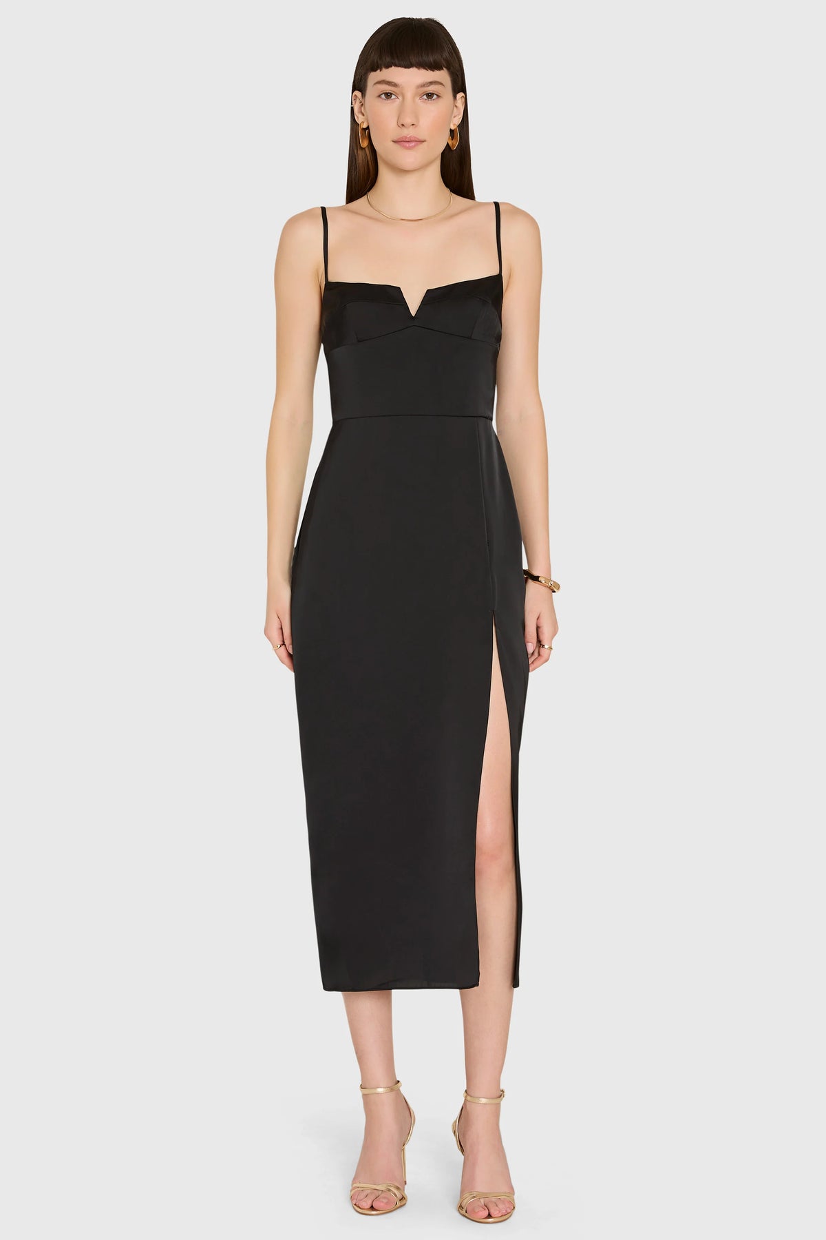 Woman wearing a black dress with a slit on a white background