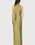 A woman viewed from the back wearing a sleeveless, high-neck, floor-length dress in a muted olive green satin-like fabric against a light gray studio background.