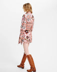 A woman shown from the back wearing a pink and multicolor paisley print wrap jacket over a light pink top, paired with brown knee-high leather boots, against a plain white studio background.