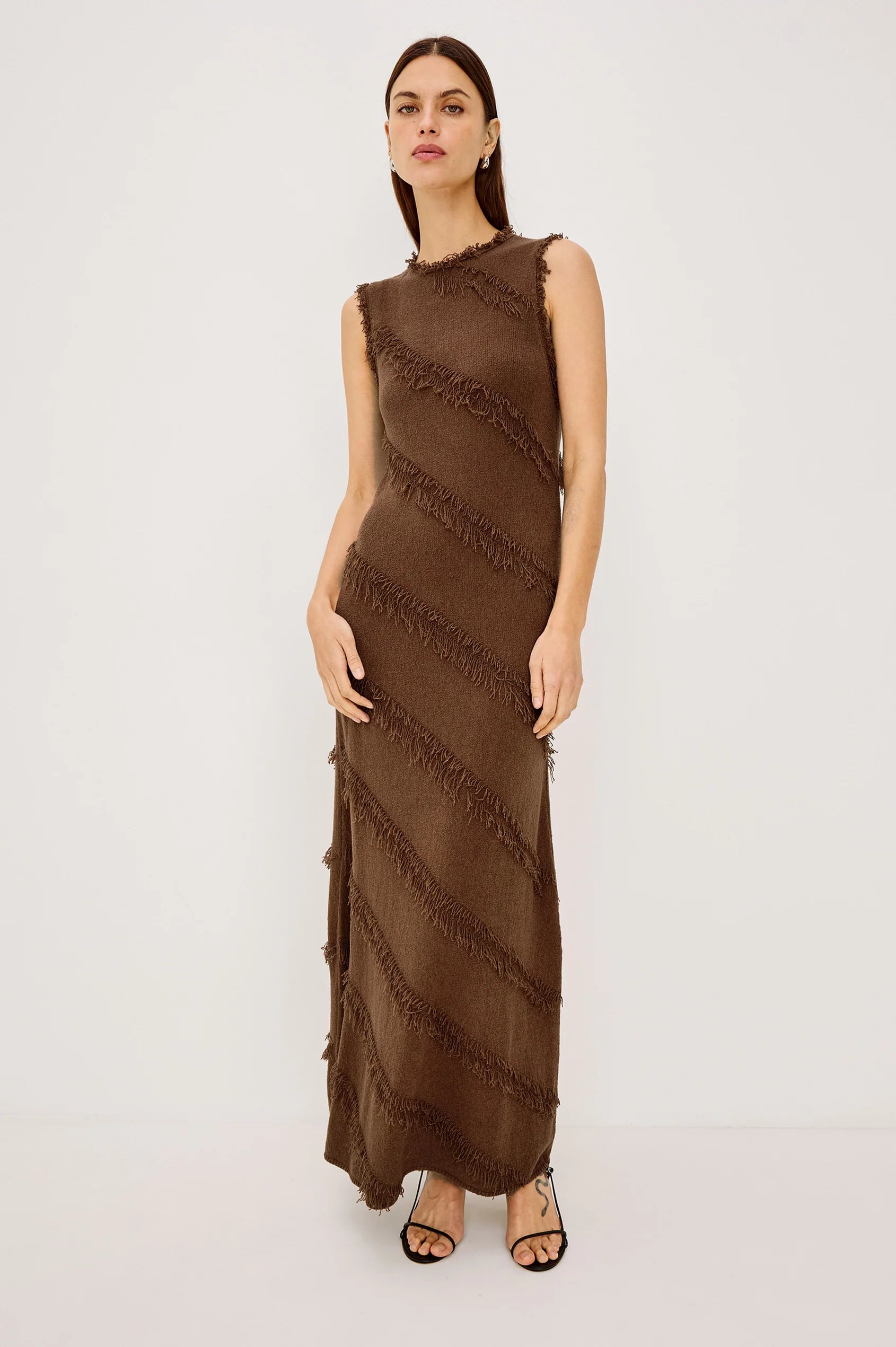 Woman wearing a brown sleeveless dress with fringe details on a white background