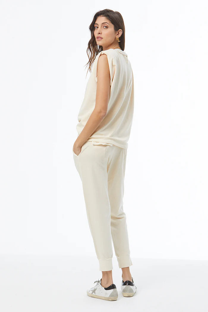Woman wearing a cream-colored outfit on a white background, back