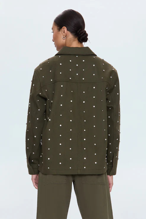 Person wearing a green jacket with rhinestones on a light background