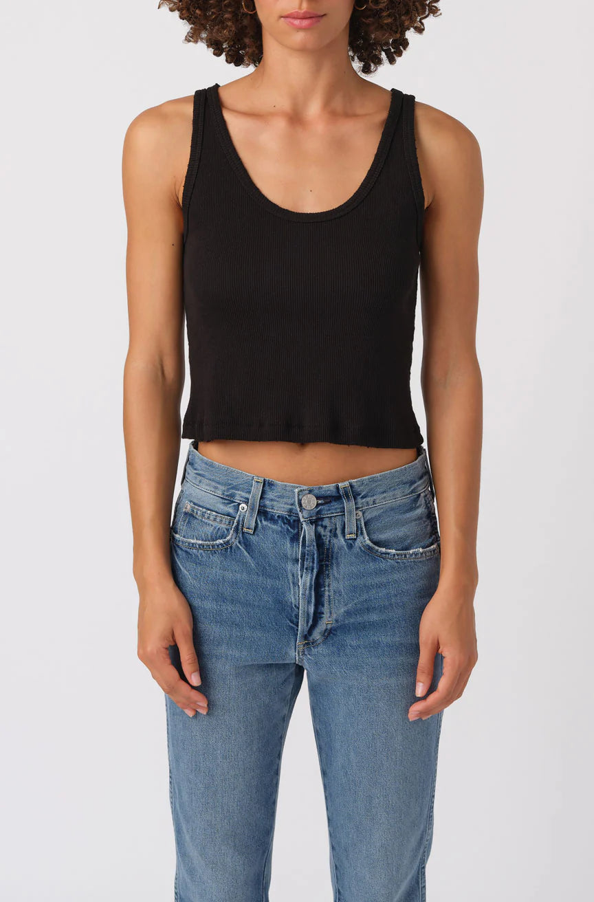Person wearing a black tank top and blue jeans on a white background