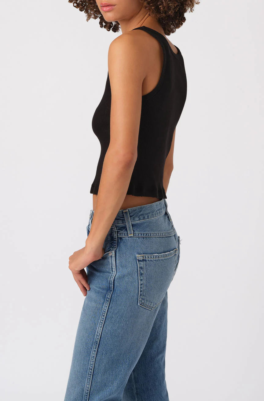 Person wearing a black sleeveless top and blue jeans on a white background