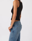 Person wearing a black sleeveless top and blue jeans on a white background