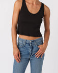 Person wearing a black tank top and blue jeans on a white background