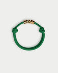 Green bracelet with gold beads on a white background