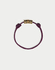 Purple bracelet with gold beads on a white background