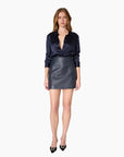 model wearing a leather navy skirt and long sleeve navy top on a white background