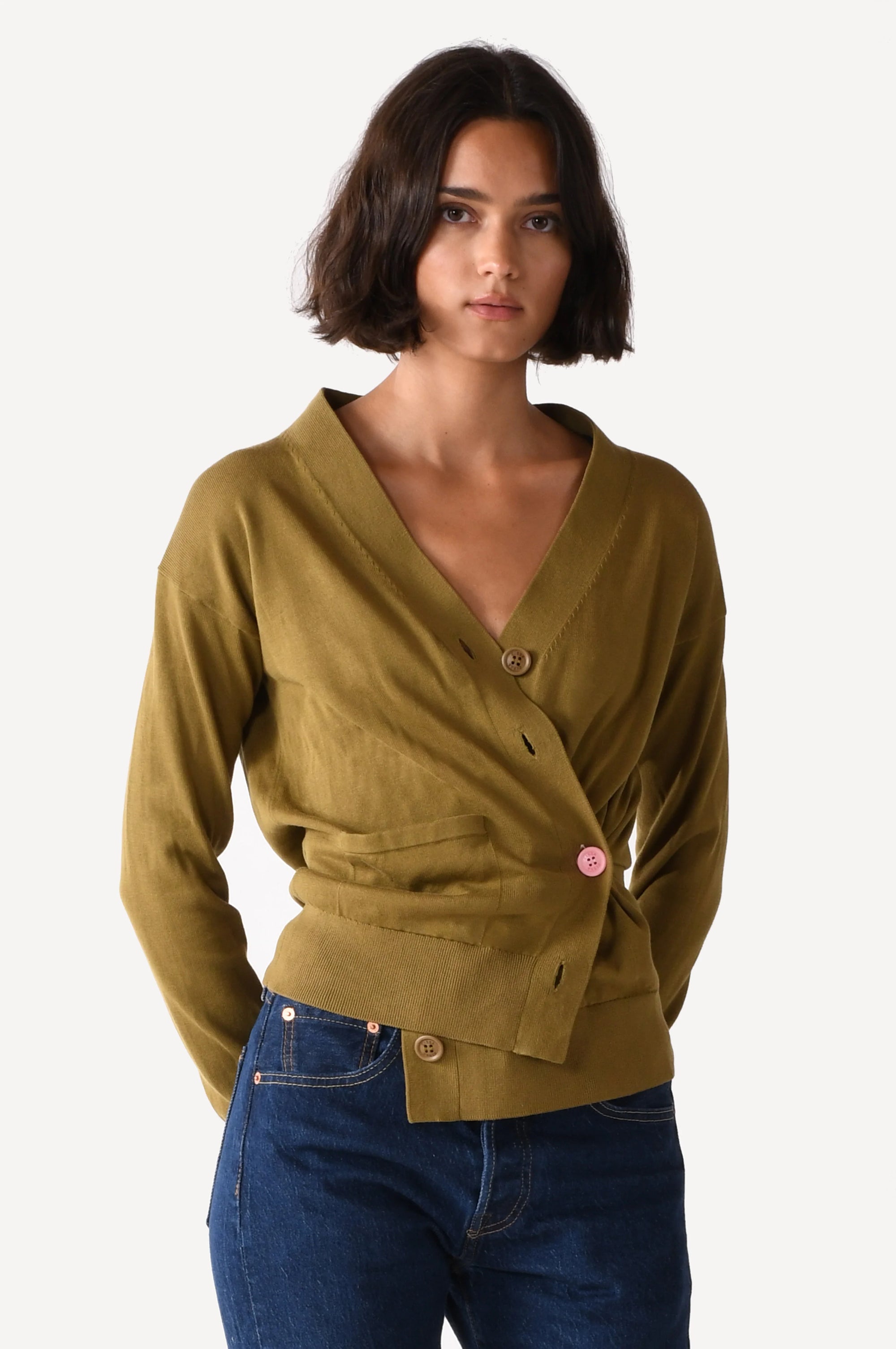 Woman wearing a green cardigan over a blue top on a white background