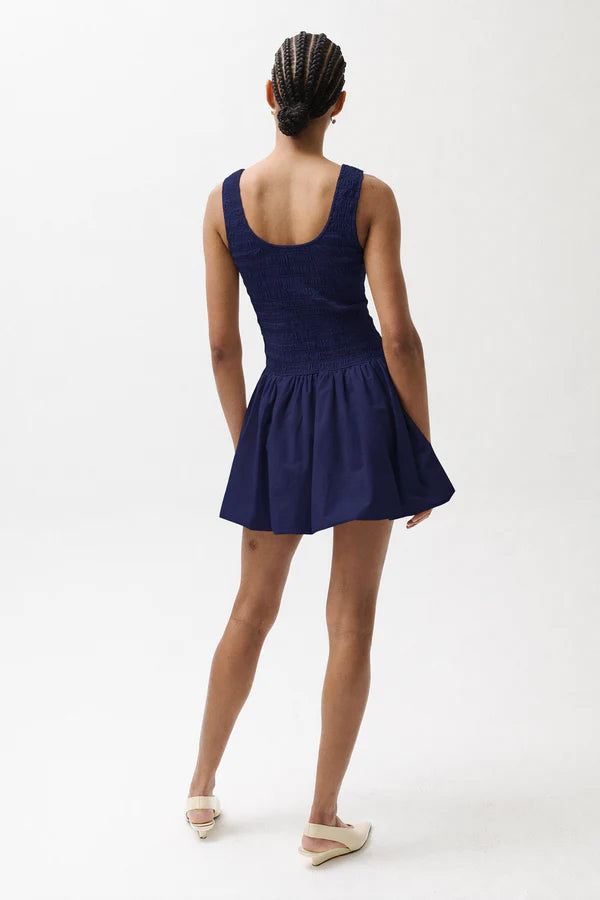 Person wearing a navy blue dress on a white background