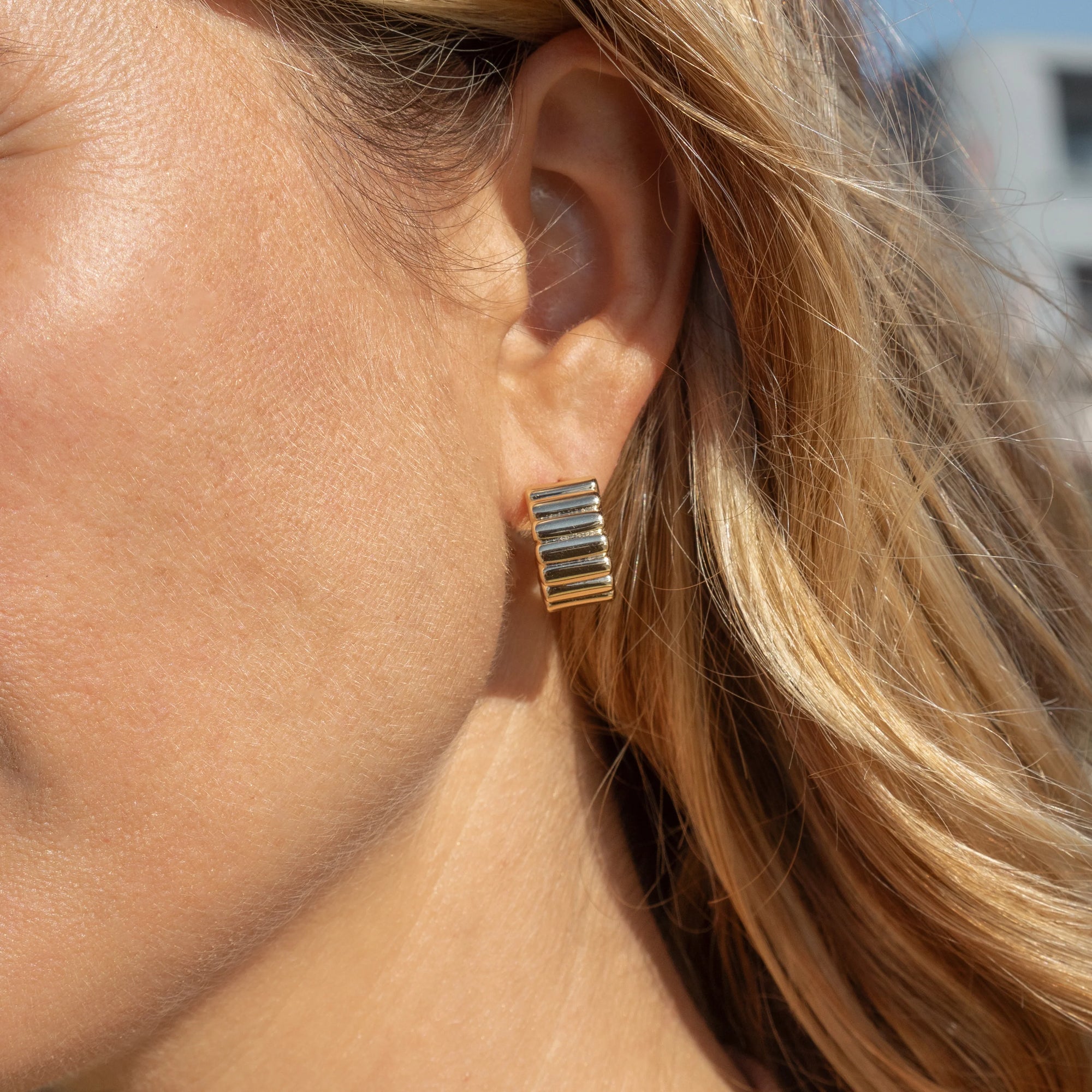 Close-up of a person wearing gold earrings.