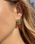 Close-up of a person wearing gold earrings.