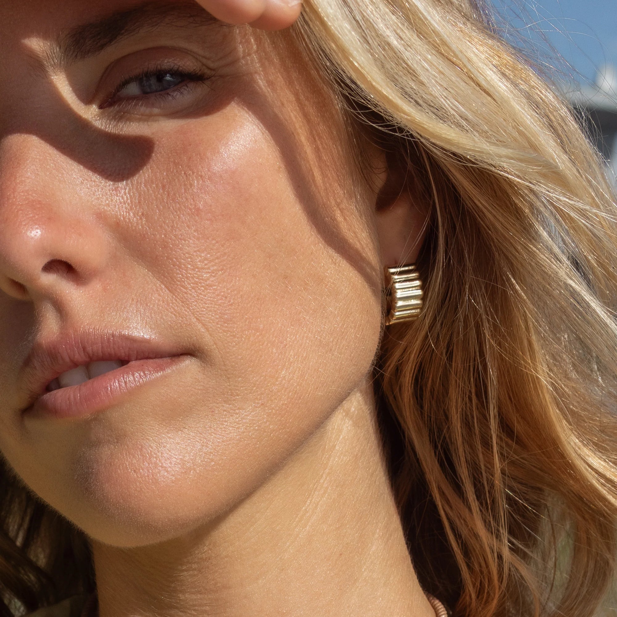 Close-up of a woman wearing gold earrings with a blurred background