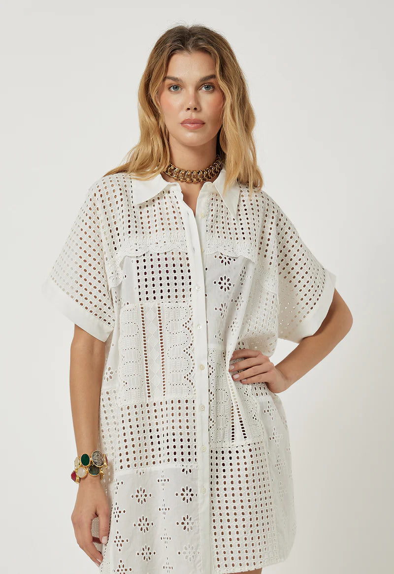 Woman wearing a white crochet dress on a plain background