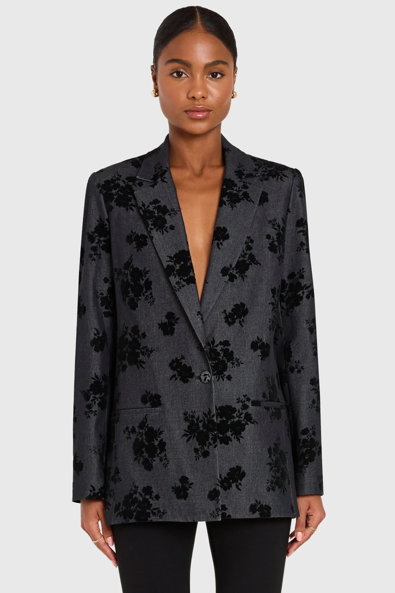 Woman wearing a dark floral blazer on a white background front