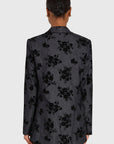 Person wearing a black floral patterned blazer on a white background, back