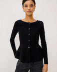 model wearing a black button down peplum caridgan with jeans on a grey background