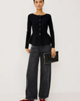 model wearing a black button down peplum caridgan with jeans on a grey background