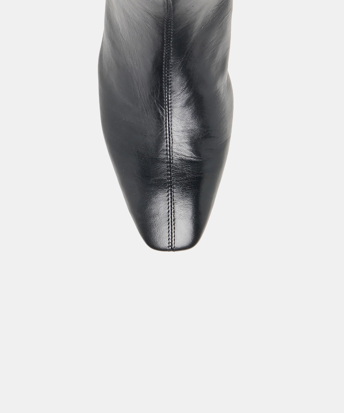 Close-up of a black leather boot showing the pointed toe and center seam against a light gray background.
