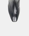 Close-up of a black leather boot showing the pointed toe and center seam against a light gray background.