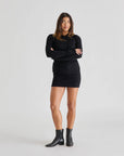 Woman wearing a black outfit with a sweater and skirt on a white background