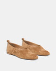 A pair of tan suede flat shoes with pull tabs, shown from a three-quarters angle on a light gray background.