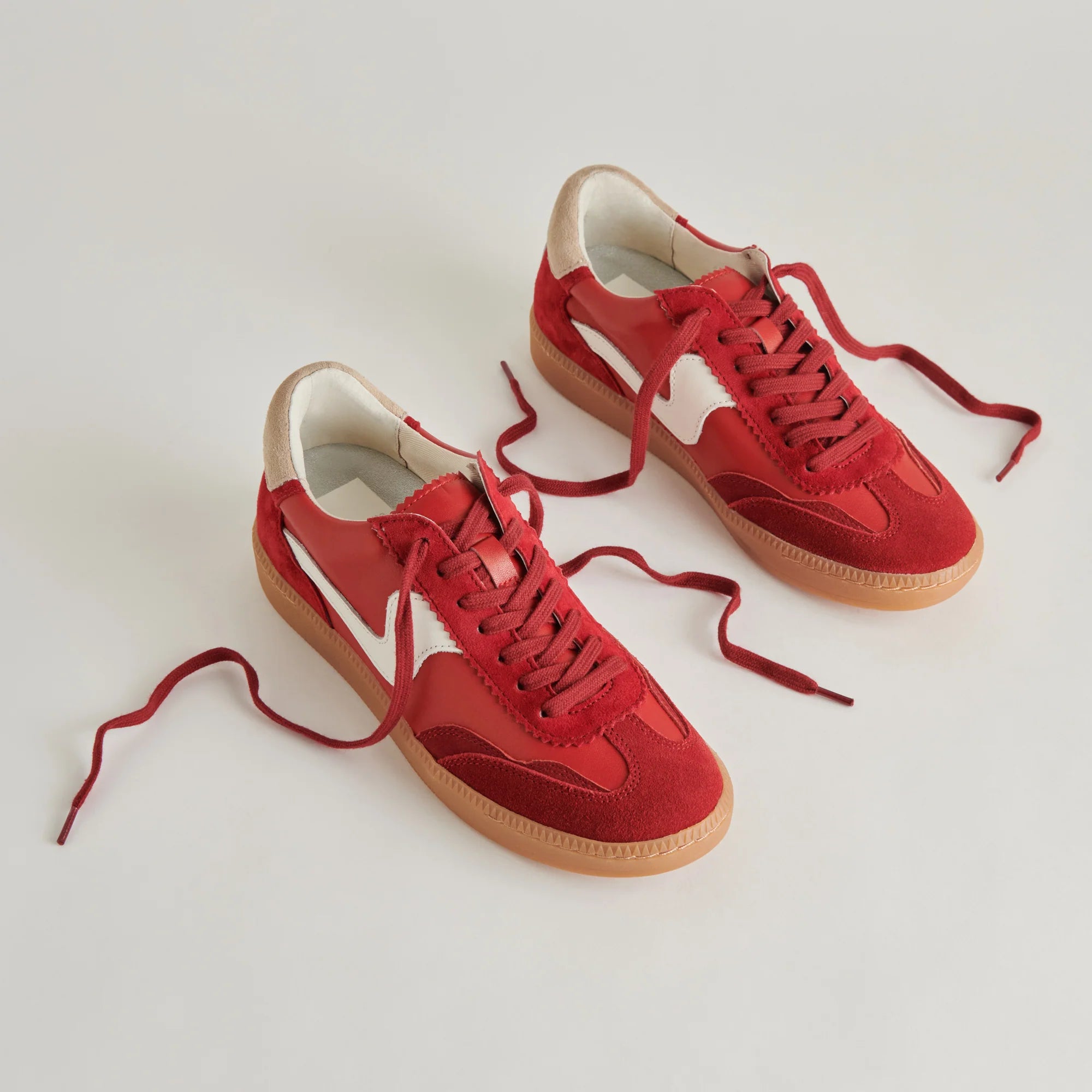 Red sneakers with brown soles on a light gray background