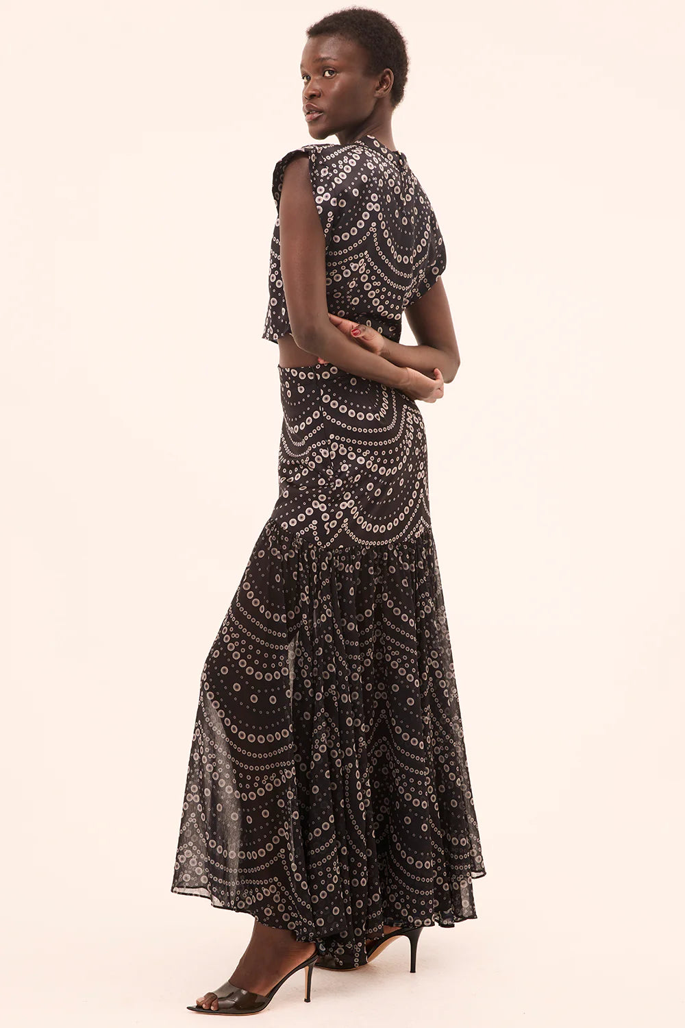 model wearing the yara skirt in stranded pearl with a matching top on a cream background side view