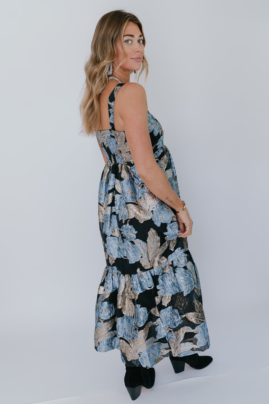 model wearing a floral metallic dress on a white background, back view 