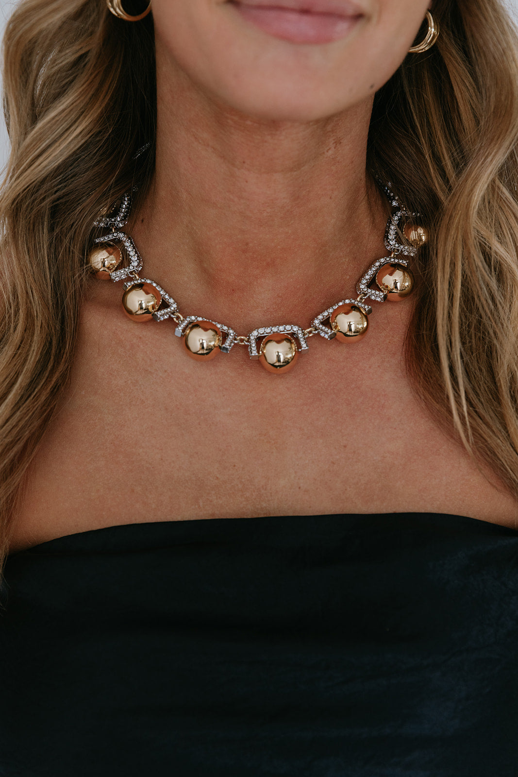 Close-up of a necklace with gold and silver beads worn by a person with blonde hair.