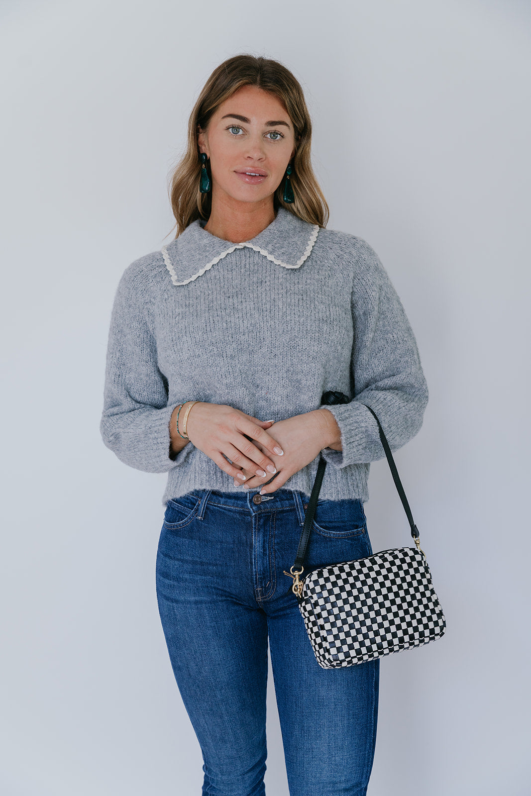 model wearing grey crochet collar cardigan with jeans and a black and white checker bag on a white background