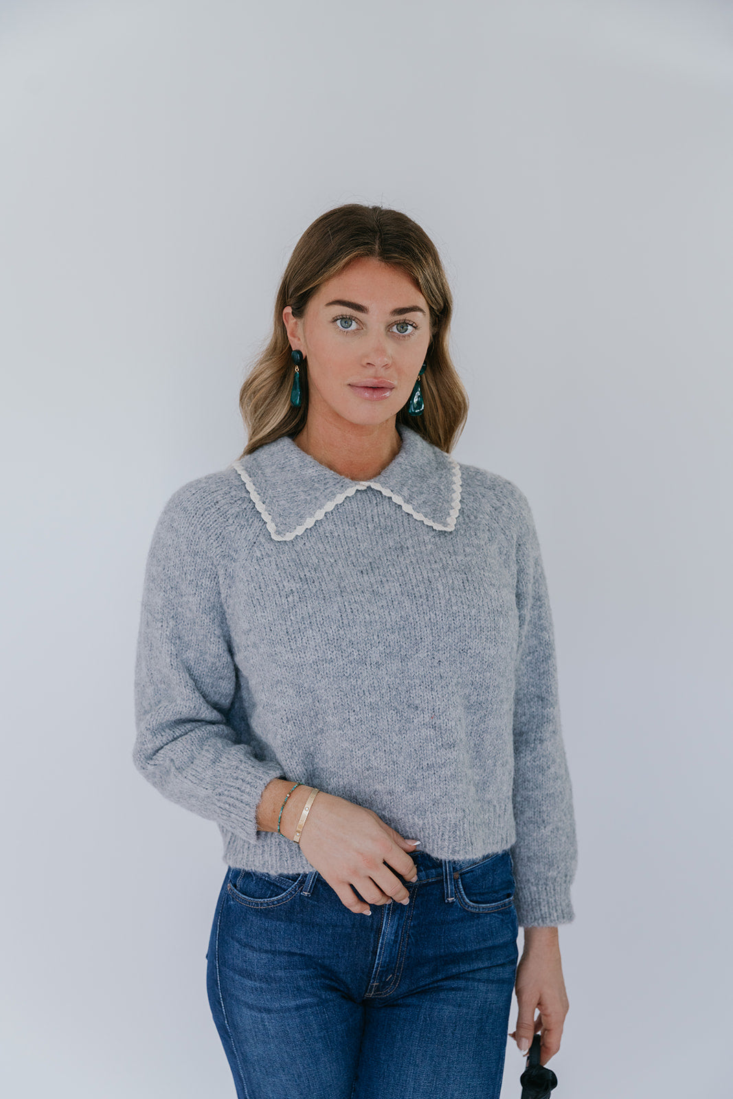 model wearing grey crochet collar cardigan with jeans on a white background