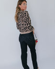 model wearing the leopard windsor cardigan with jeans and a shearling bag with a heart fob on a white background, back