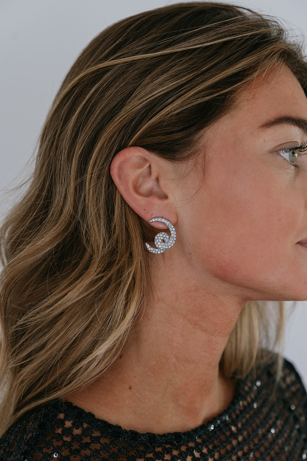 pave earrings on a model wearing a black dress with a white background
