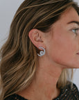 pave earrings on a model wearing a black dress with a white background