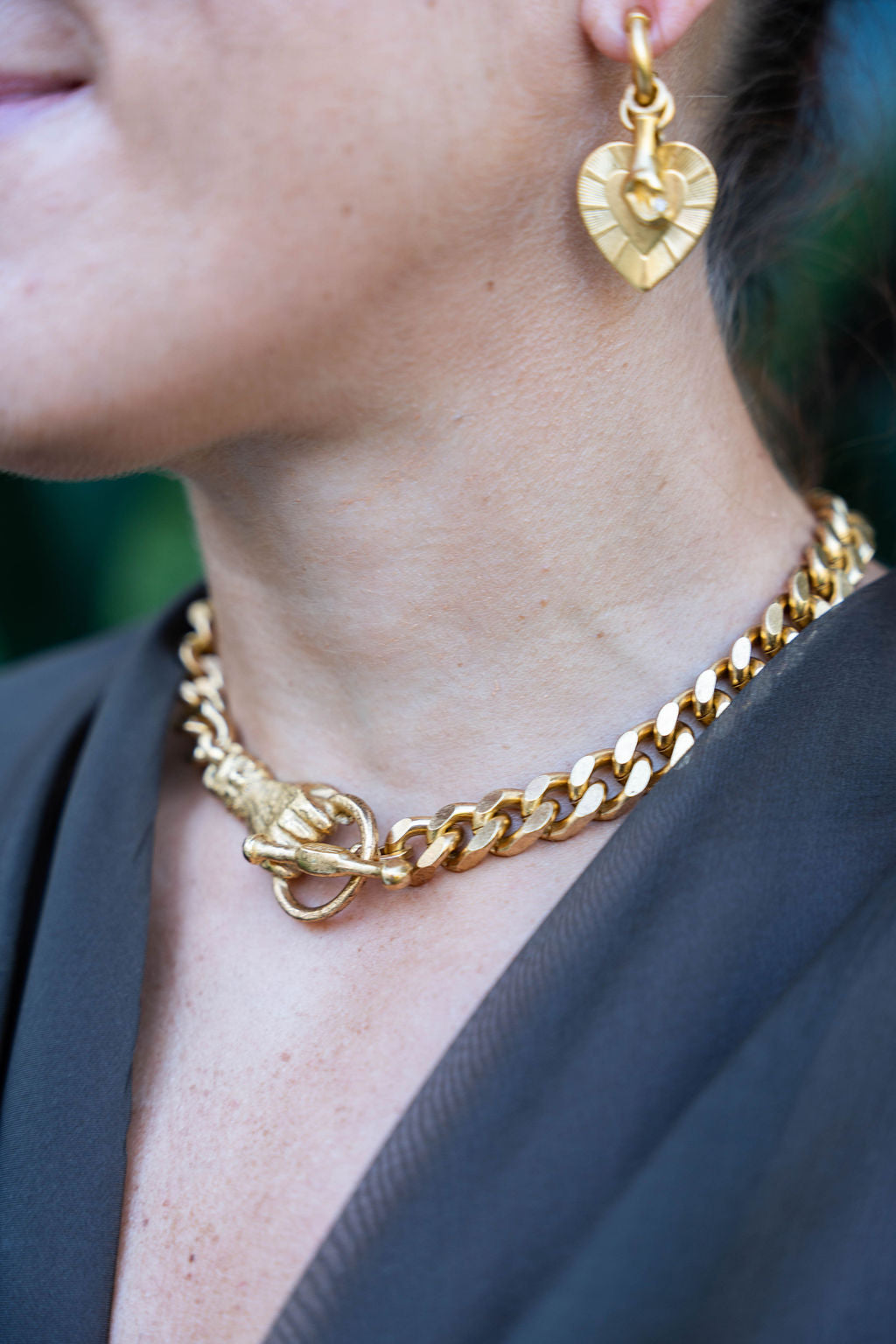 Gold chain necklace and heart-shaped earrings on a person