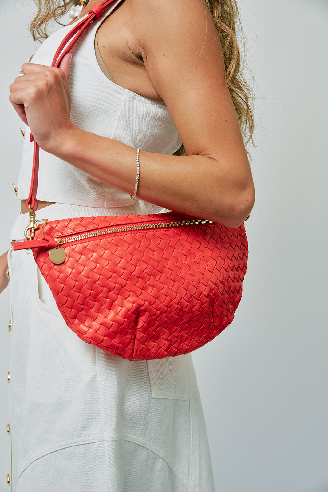 Person holding a red woven handbag against a plain background