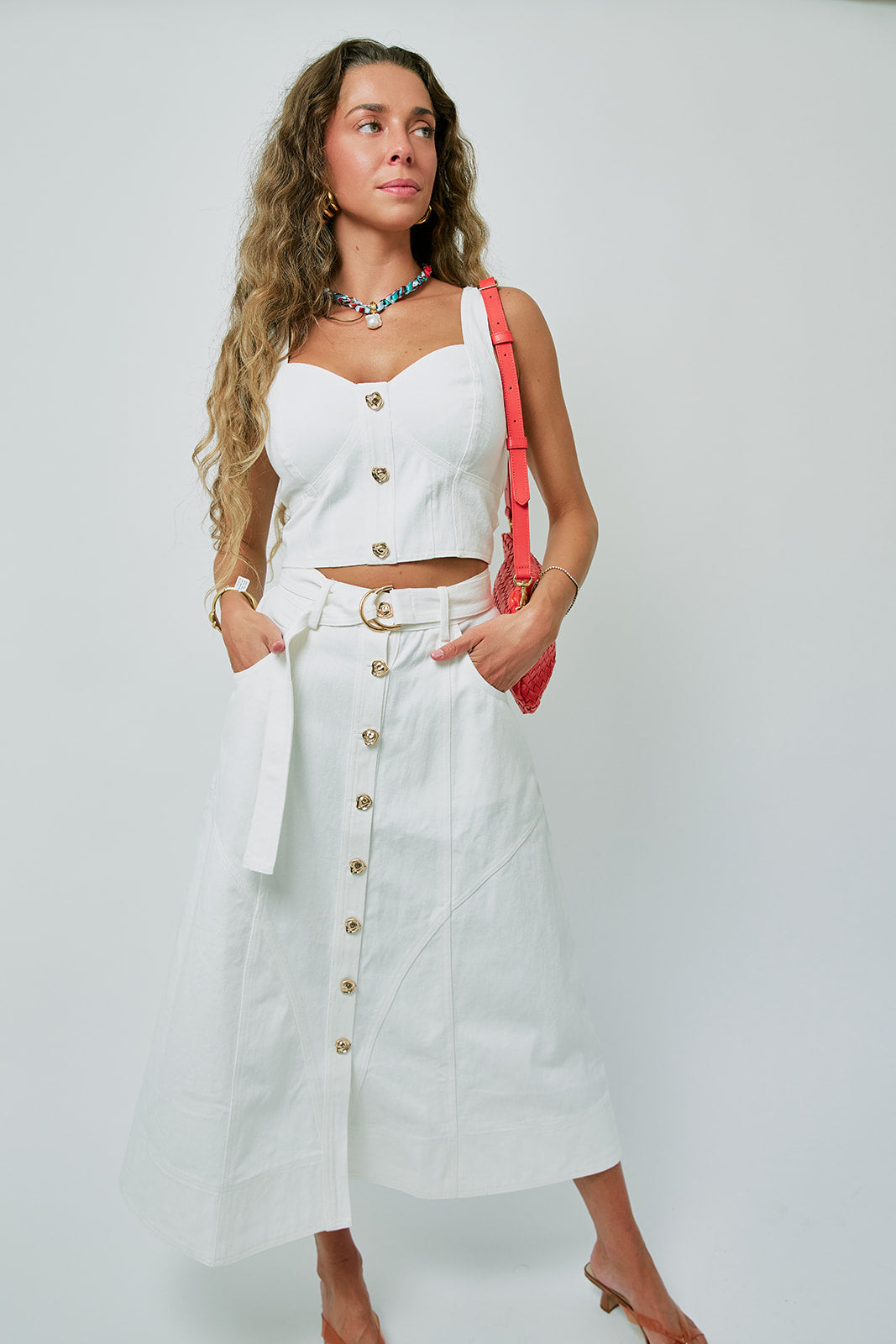 Woman wearing a white outfit with gold buttons against a light gray background, full body front