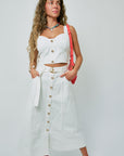 Woman wearing a white outfit with gold buttons against a light gray background, full body front