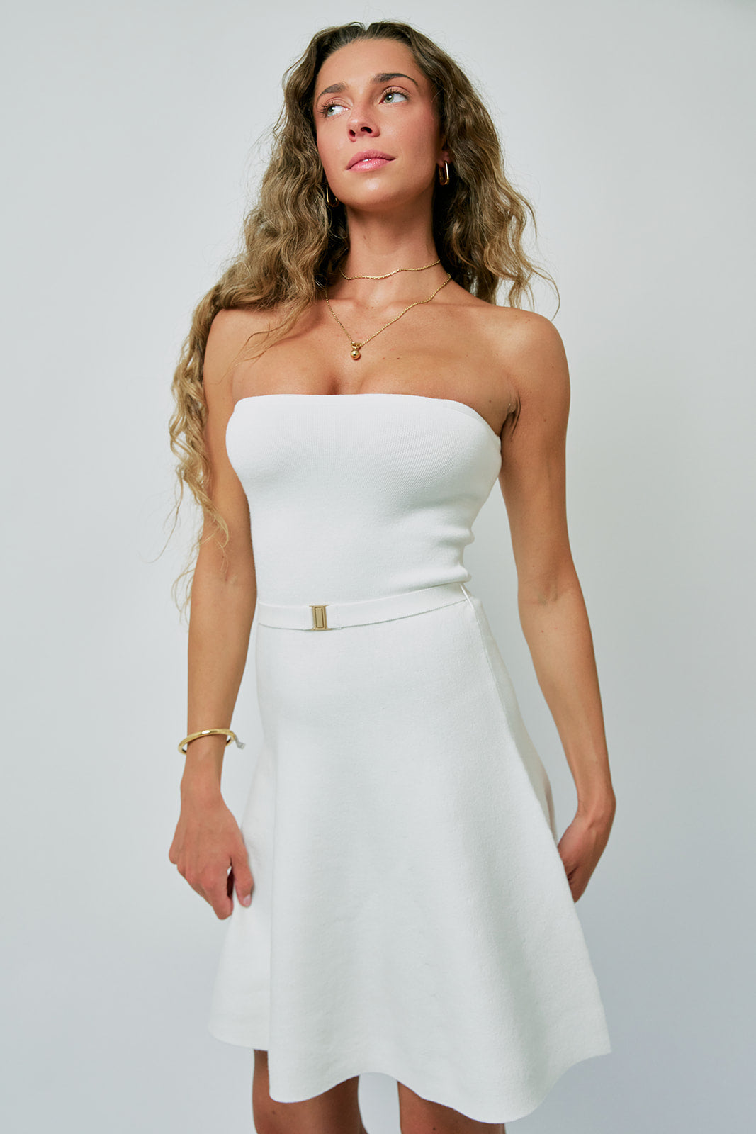 Woman wearing a white strapless dress against a plain background with Constance Wrap