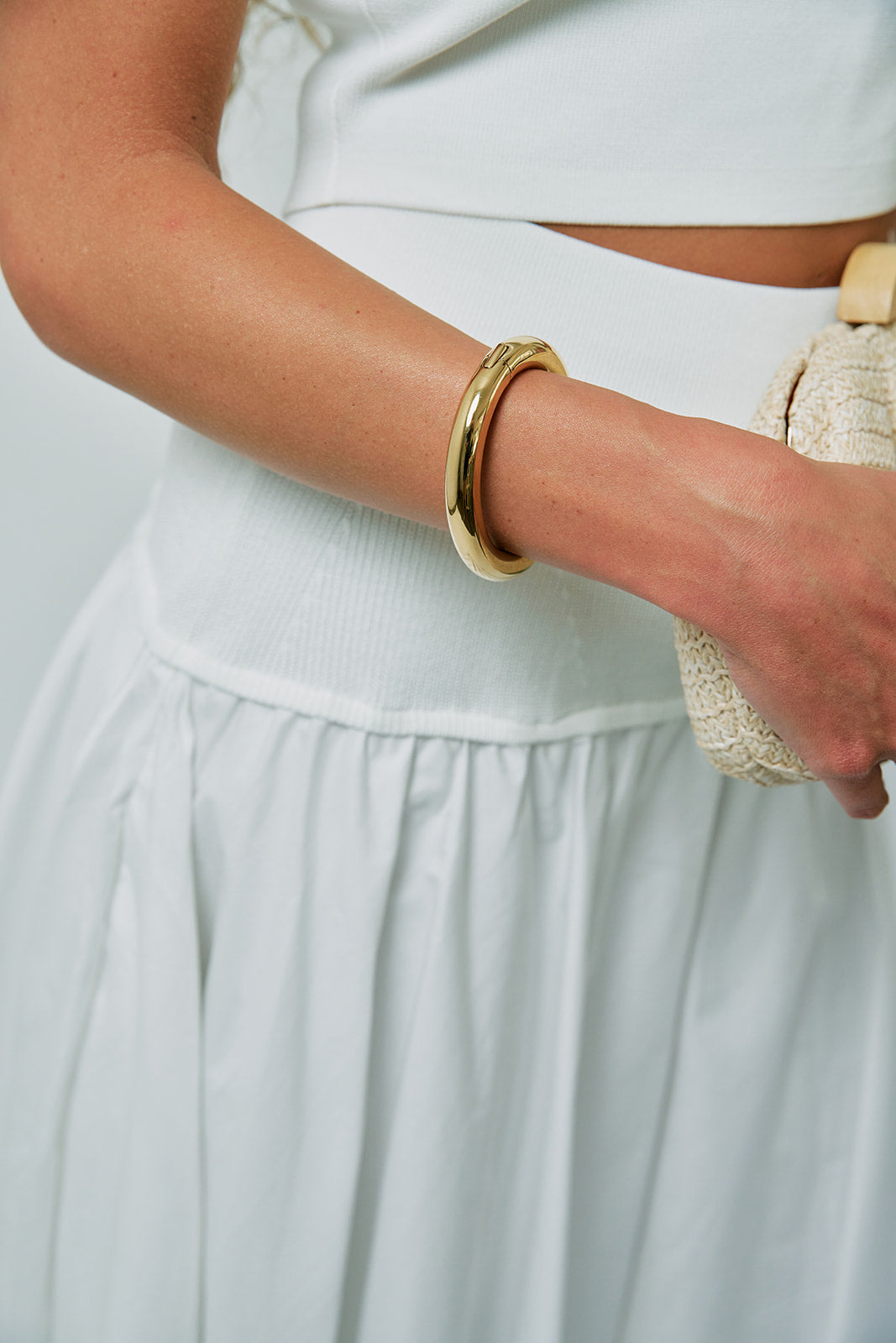 Gia Mega Bangle in Gold on wrist with white outfit